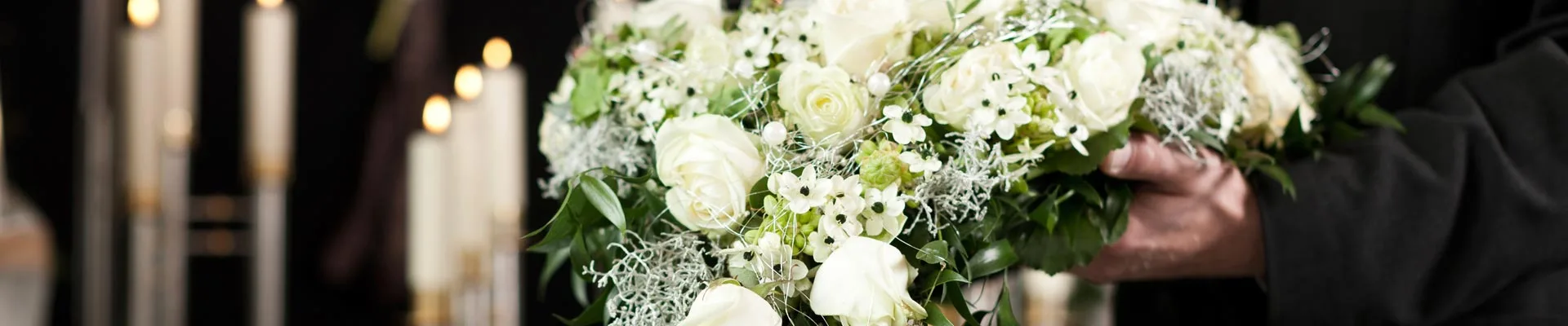 Bestattungsblumenstrauss in Weiss mit Kerzen im Hintergrund